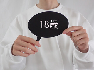 若い男性が持っている吹き出しに18歳の文字