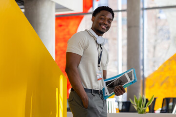 Confident black young student with headphones holding tablet