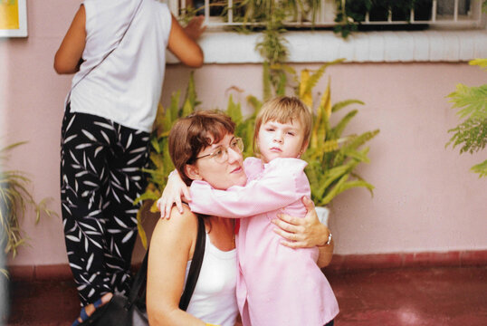 Mother hugging her daughter in school uniform, early 2000s