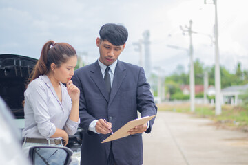 A concerned female and male insurance agent discuss a recent car accident, while a confident...