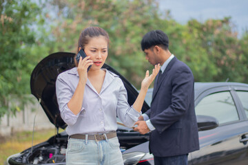 A confident businesswoman stands next to her broken car, asking for help. Frustrated but calm, she...