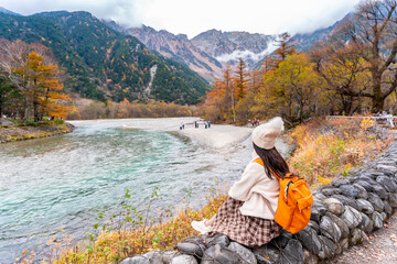 Young couple tourist relaxing and enjoying with beautiful nature autumn foliage at kamikochi in Japan