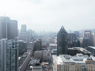 Drone flight in the downtown city skyline, foggy daytime view of Montreal, Quebec, Canada