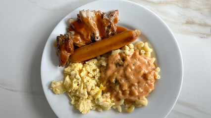 Traditional english breakfast - scramble egg, sausages, macaroni and bacon