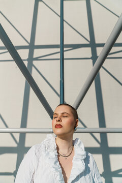 Person in white ruffled shirt standing in sunlit shadows