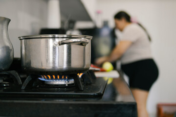 Colombian woman cooking food in pot on gas stove