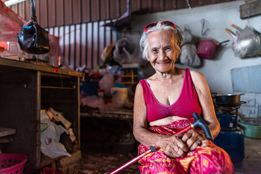 Elderly woman smiling in old home during hot day in Thailand