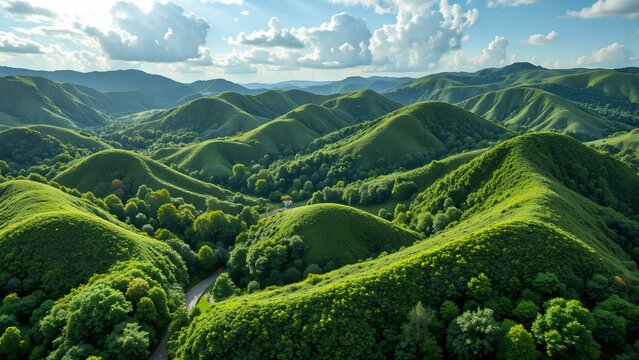Rolling green hills covered in lush vegetation under a partly cloudy sky, creating a peaceful and scenic natural landscape.