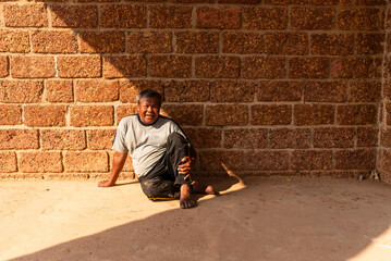 Elderly Thai man resting by temple wall with a smile in urban Thailand