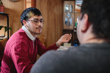 Gay couple talking and drinking tea in their modest home