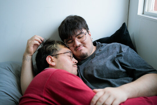Latin gay couple cuddling in bed