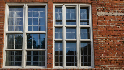 Fototapeta premium Architectural Beauty: A close-up captures the allure of a historic building with intricate windows, standing out against a backdrop of rustic brick.