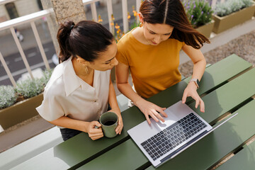 Two businesswomen working on laptop on balcony
