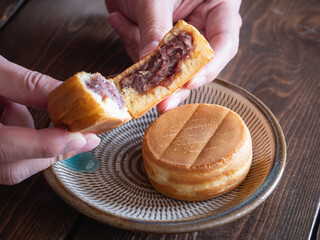 焼き菓子の"おやき"を半分にして食べる。生地であんこを包んだ和菓子。大判焼き、今川焼きとも言う。