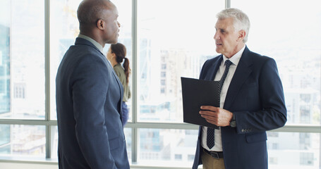 Business men, documents and discussion in lobby, report and insight for project at insurance agency. Mature people, CEO and employee with paperwork, listening and perspective with advice at company