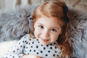 Cute red haired girl sitting in a chair and smiling at the camera