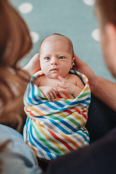 Mother amd father holding their baby. The baby is staring at them.