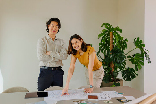 Architects reviewing plans in modern office with plants