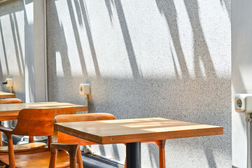 Empty wooden table and chairs in the cafe or coffee shop. Grey or gray wall with shadows reflection. copy space, empty, free, negative.