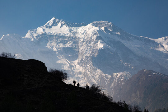 Silhouette of trekkers against mount Annapurna II.