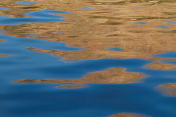 Abstract blue and brown reflections on rippled water surface. Background with abstract natural shapes and vibrant colors.