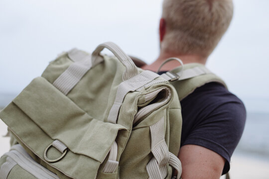 Close-up of a khaki canvas backpack on a male traveler by the ocean