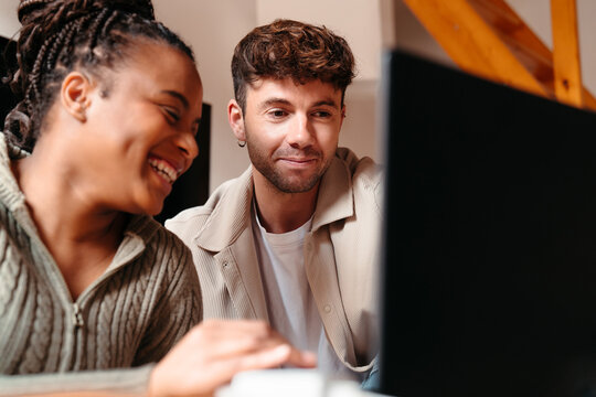 Happy multiracial couple at home looking at computer