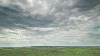 A Vast and Expansive Green Field Stretching Under an Enormous, Dramatic Cloudy Sky Time lapse.