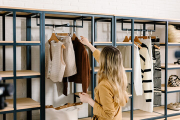 Back view of a woman holding a brown jacket inside a clothing store