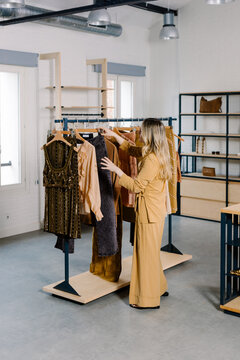Woman picking a pair of denim pants from a rack inside a boutique
