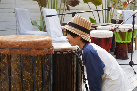Asian boy observing African drums on outdoor stage