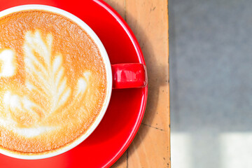 Extreme Close up view of hot cafe latte in the red cup. Wooden table, grey or gray floor, corner. Copy space. Coffee. Latte art. Top, above, high angle, Half. Dark, shadows, Black.