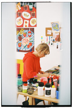 Artist sketching in a colorful, decorated studio with art on wal