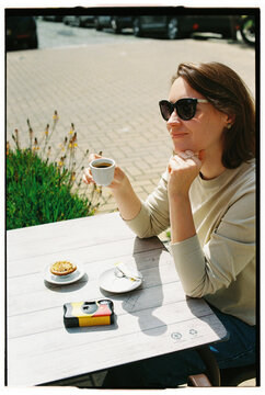 Smiling woman with espresso at outdoor table