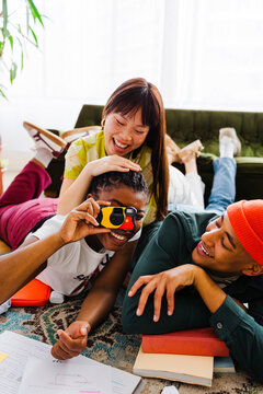 Happy students taking photos and studying together at home