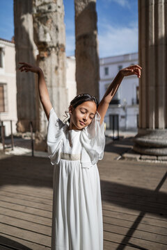 Portrait of a girl in a pretty dress dancing in a Roman temple.