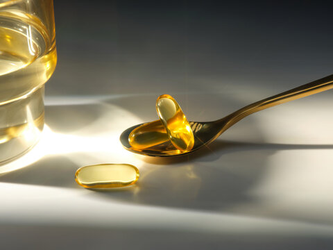 Close-up shot of fish oil capsules on a golden spoon