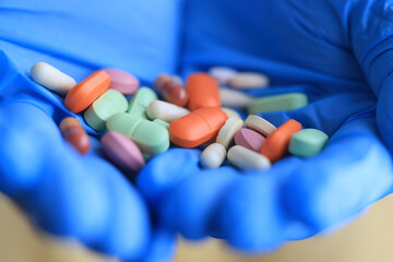 bunch of different pills in the hands of a doctor in blue gloves close-up background pharmacy