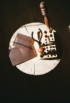 Leather Craft Tools and Wallets on Wooden Surface
