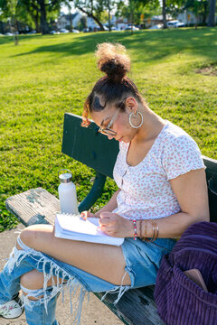writing in notebook on bench