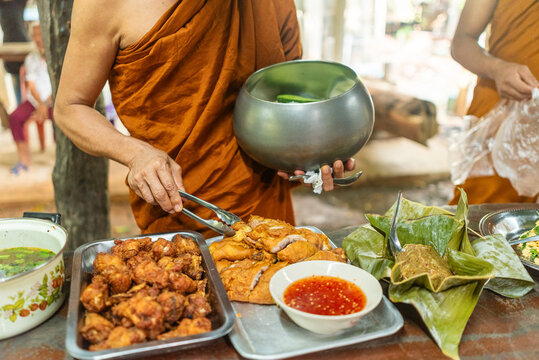 Thai Buddhist monk filling his alms bowl during a religious ceremony i