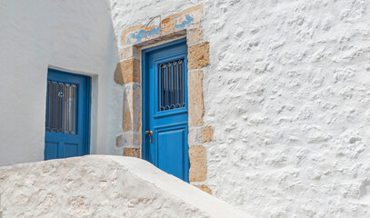 white facade wih blue doors of a traditional greek house