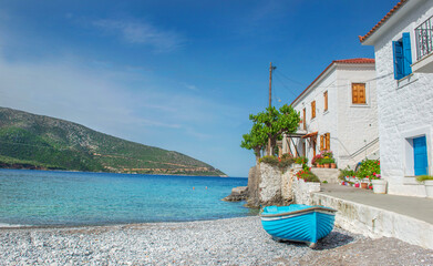 white house with colorful shutters of a seaside village with boats on the beach in Peloponnese Greece