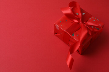 Beautiful gift box with bow on red background, top view