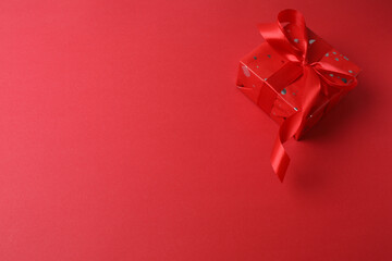 Beautiful gift box with bow on red background, top view