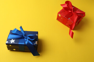 Gift box with a bow on a yellow background, top view. Space for text