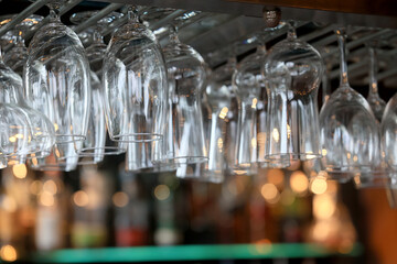 clean glass wine glasses hanging, background on the bar counter in the restaurant, abstract view of...