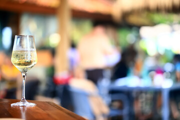 a glass of white wine served in a restaurant, abstract background of a summer restaurant