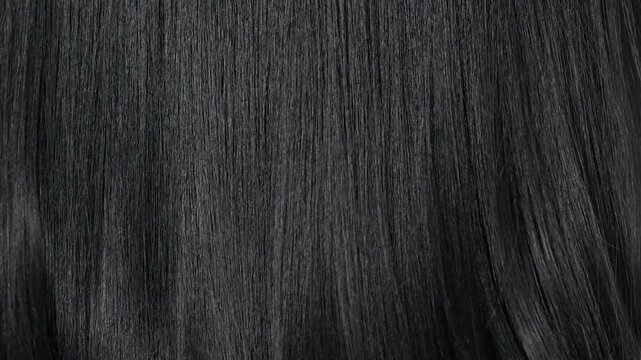Closeup human long hair texture in slow motion, black straight hair background