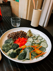 Healthy salad bowl featuring assorted vegetables and quinoa on a wooden table in a bright setting